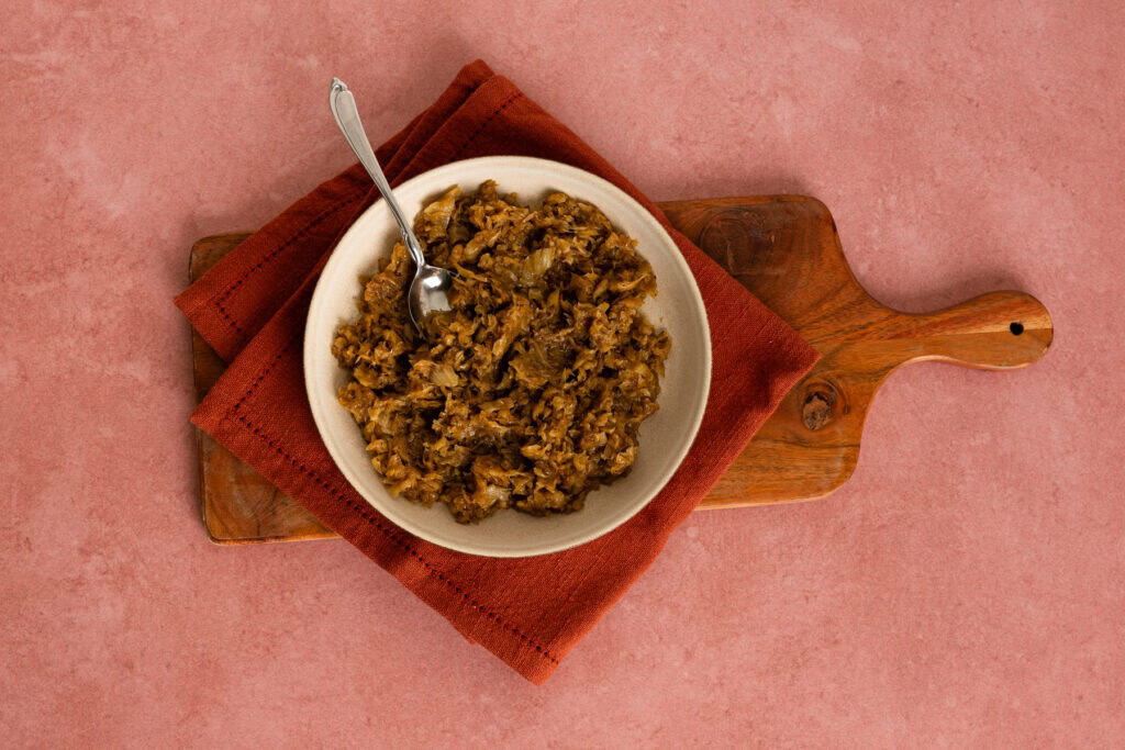 Overhead shot of a bowl of caramelized onions and fennel on a wood tray.