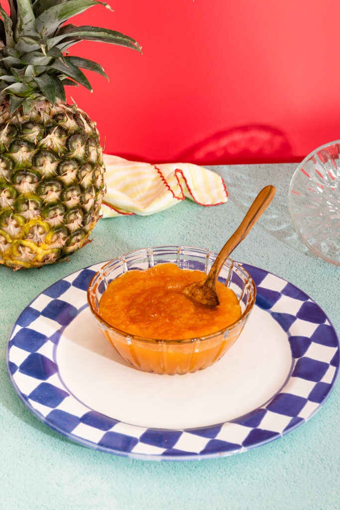 Close-up of pineapple and passion fruit jam in a glass bowl on a plate.